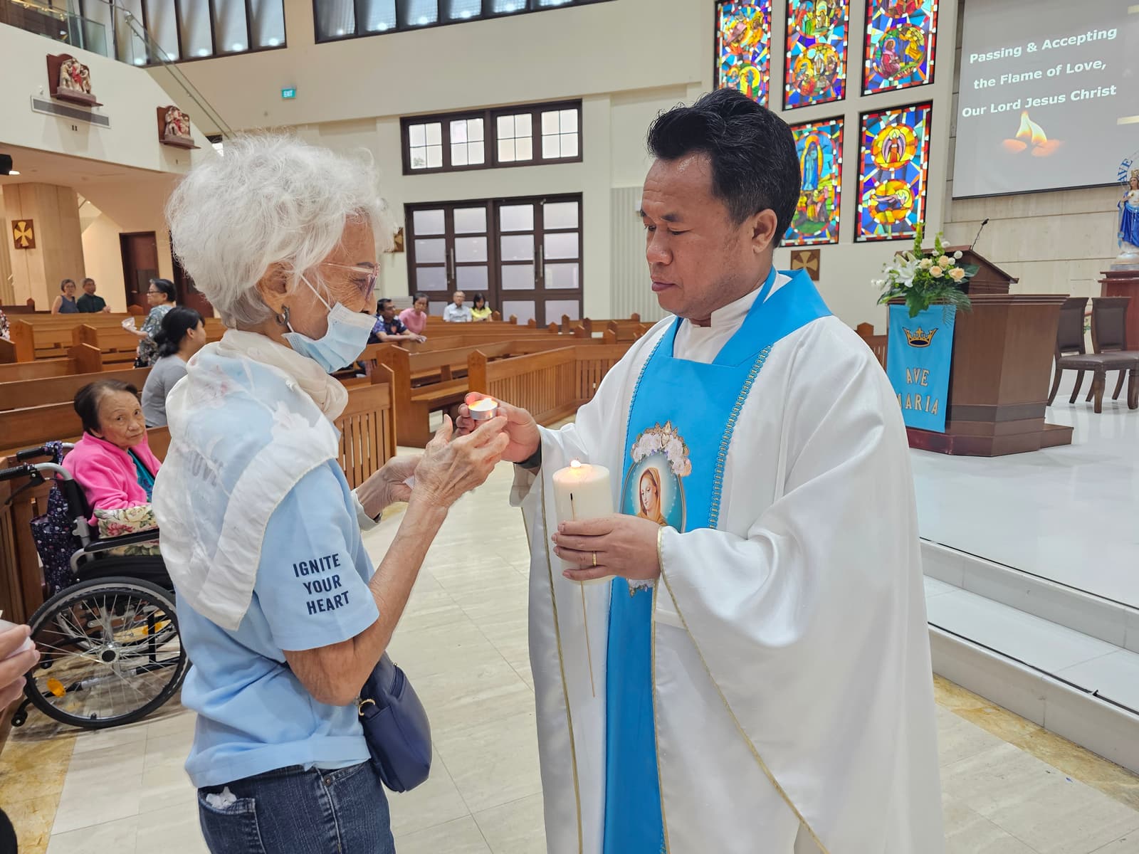 A parishioner receiving the flame from the priest, candle to candle, during Mass