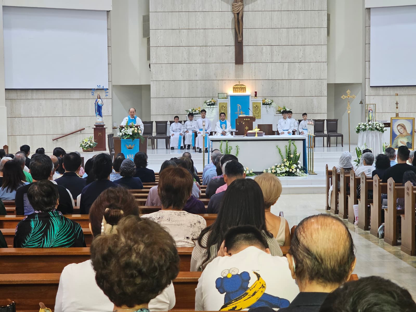 The congregation at Flame of Love Mass, the sanctuary lit and vested ministers at the altar