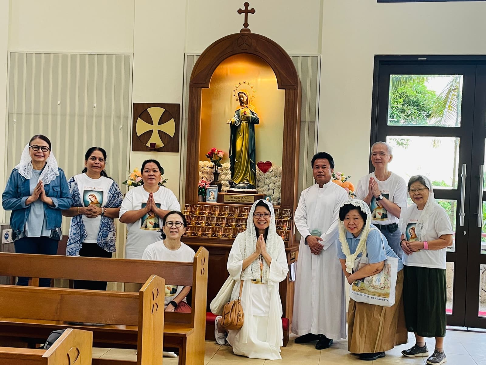 Members standing in prayer beside the Flame of Love shrine inside the church